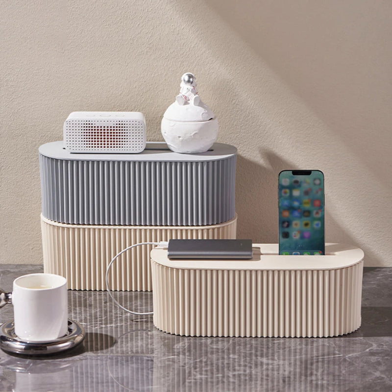 2 boîtes pour câble management de couleur blanc cassé et grise posé sur du sol marbré