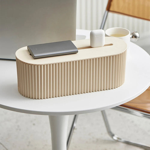 boîte pour câble management de couleur blanc cassé avec airpods posé sur une table