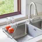 tomates et verres sur l'égouttoir organisateur d'évier pliable dans un évier de cuisine