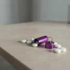 mini rangement de médicaments étanche de couleur violet avec des comprimés posé sur une table