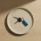 mini rangement de médicaments étanche dans un porte-clé sur une assiette posé sur une tble en bois