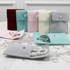 des pochettes organisateur de bijoux en velours de différentes colories avec des bijoux sur une table